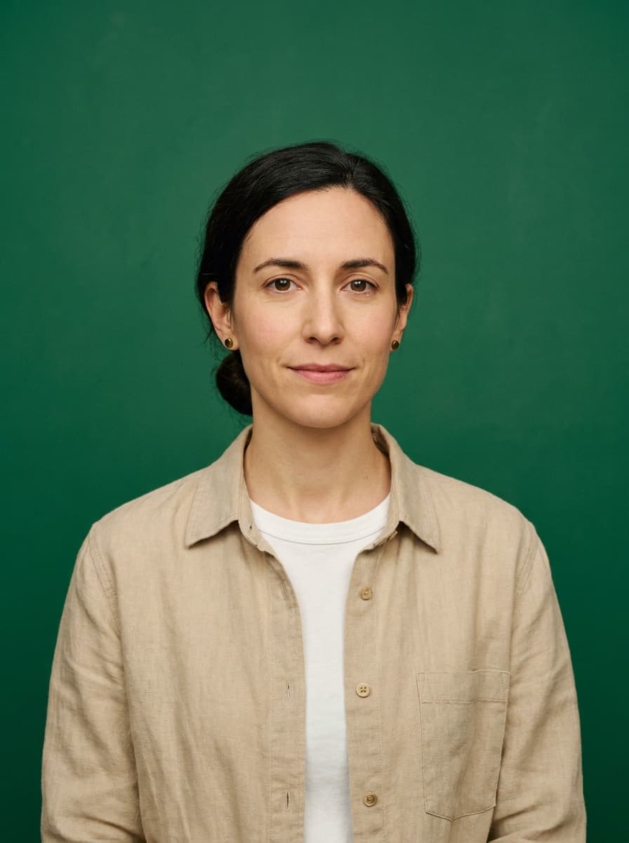 Portrait of Nadia Sammut — dark hair tied back, beige linen overshirt, on a deep green backdrop